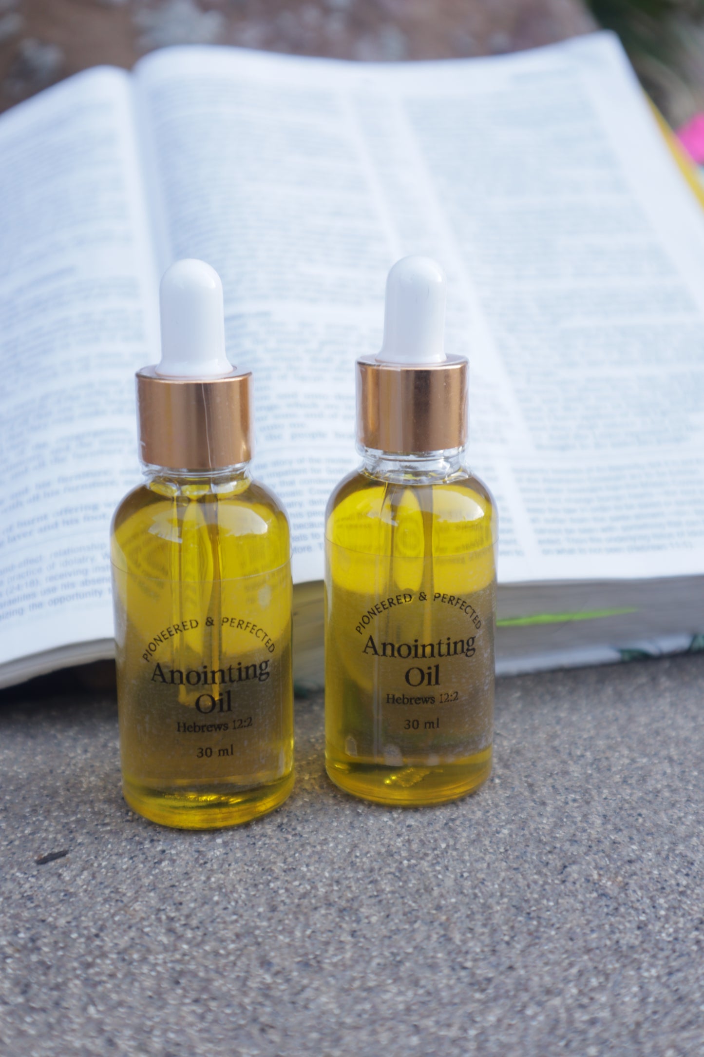 Two bottles of Anointing oil on a textured surface.