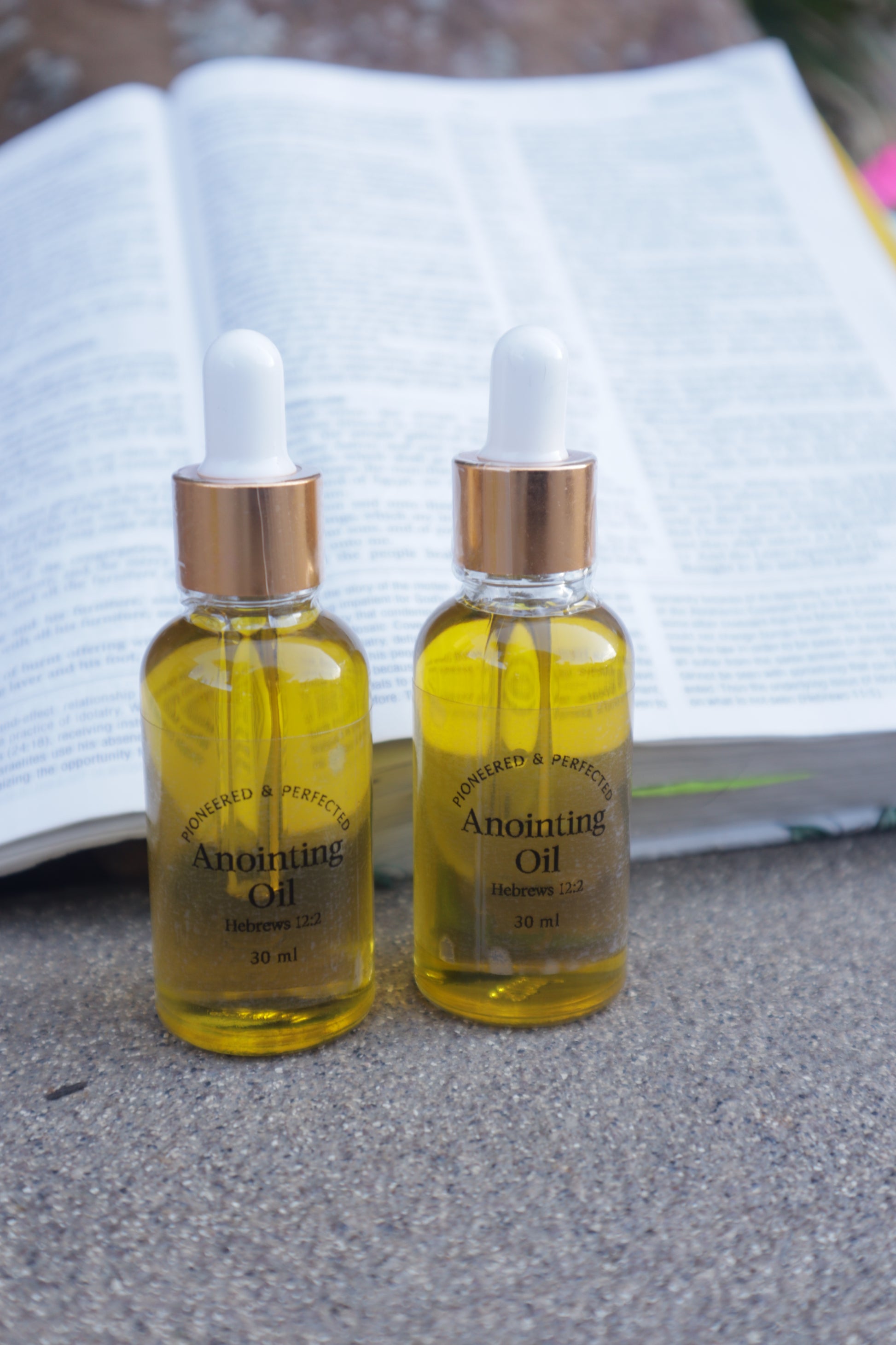 Two bottles of Anointing oil on a textured surface.